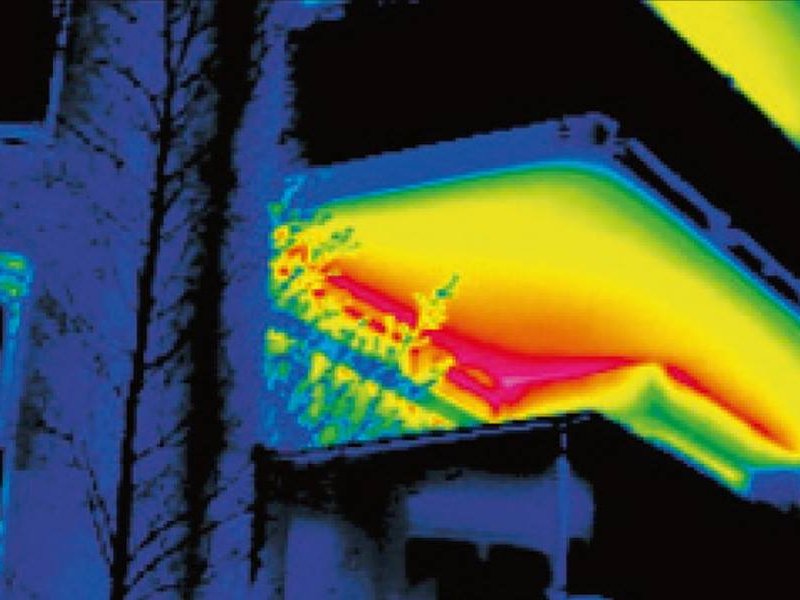 Termografski posnetek stavbe — toplotne izgube na robu strehe in balkona, vidne kot rdeče-rumena območja